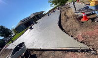 Concrete construction team working on a new driveway with ground compaction in Northern Colorado, showcasing proper site preparation and material handling.