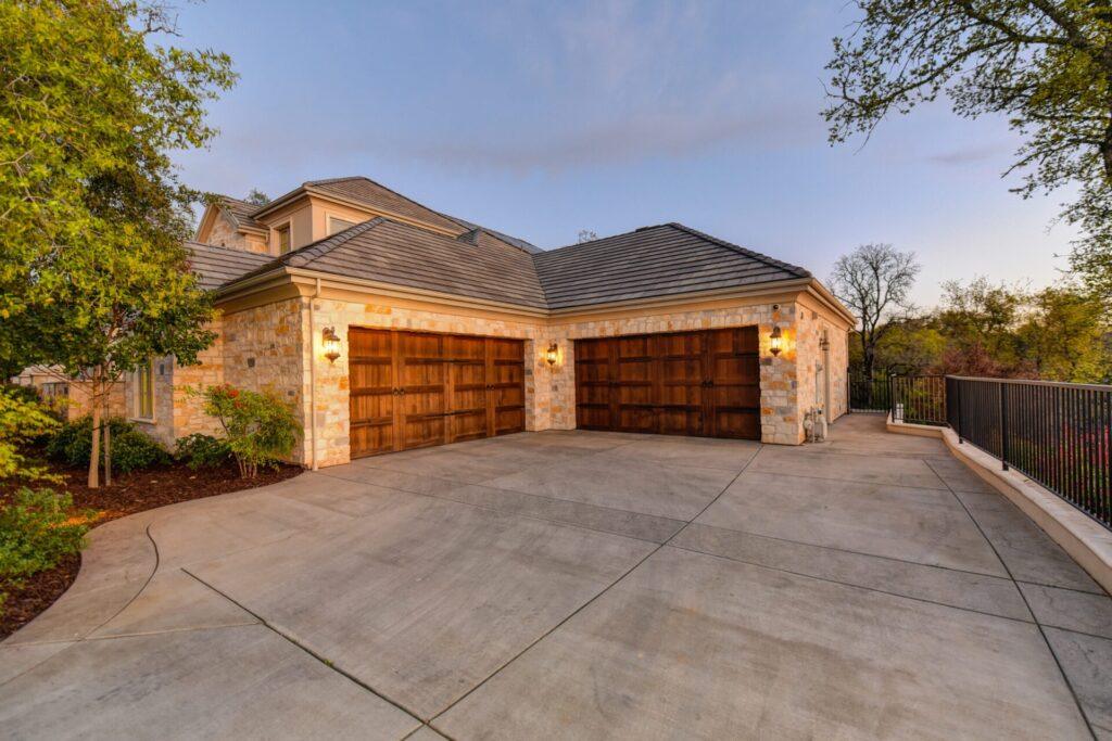 A concrete driveway leading to a two-car garage in a suburban neighborhood.