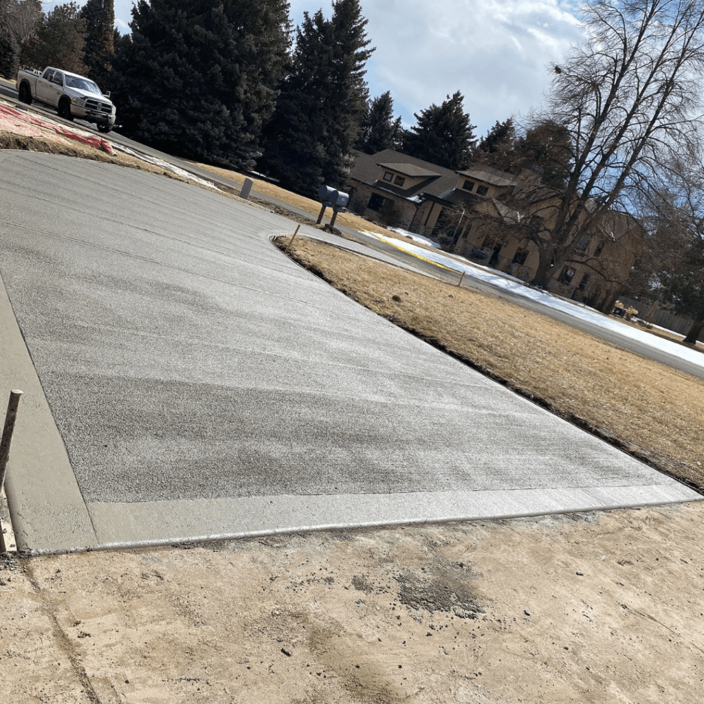 A freshly replaced, spacious, and beautifully finished concrete driveway in Loveland, CO, showcasing expert craftsmanship by Hugo’s Concrete.