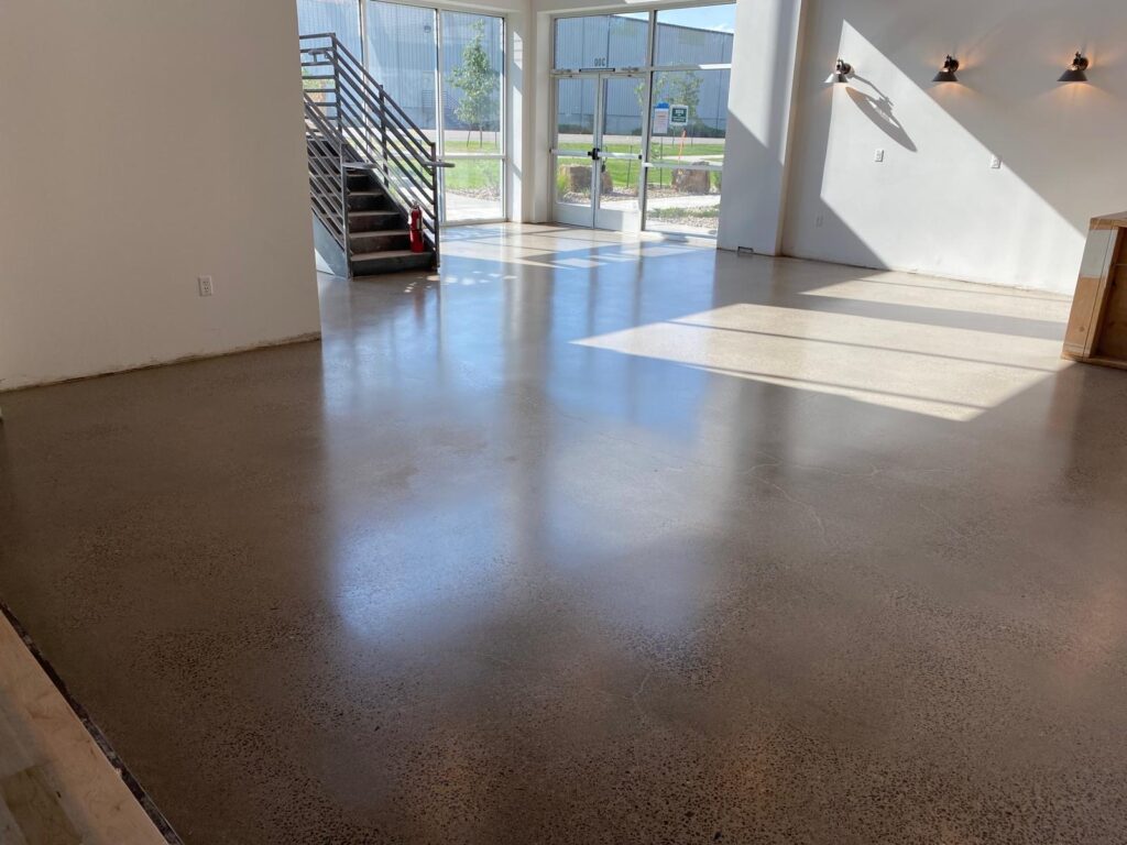 Spacious interior of a commercial property in Colorado featuring a polished concrete floor with a smooth, glossy finish, enhancing the modern aesthetic under natural light.