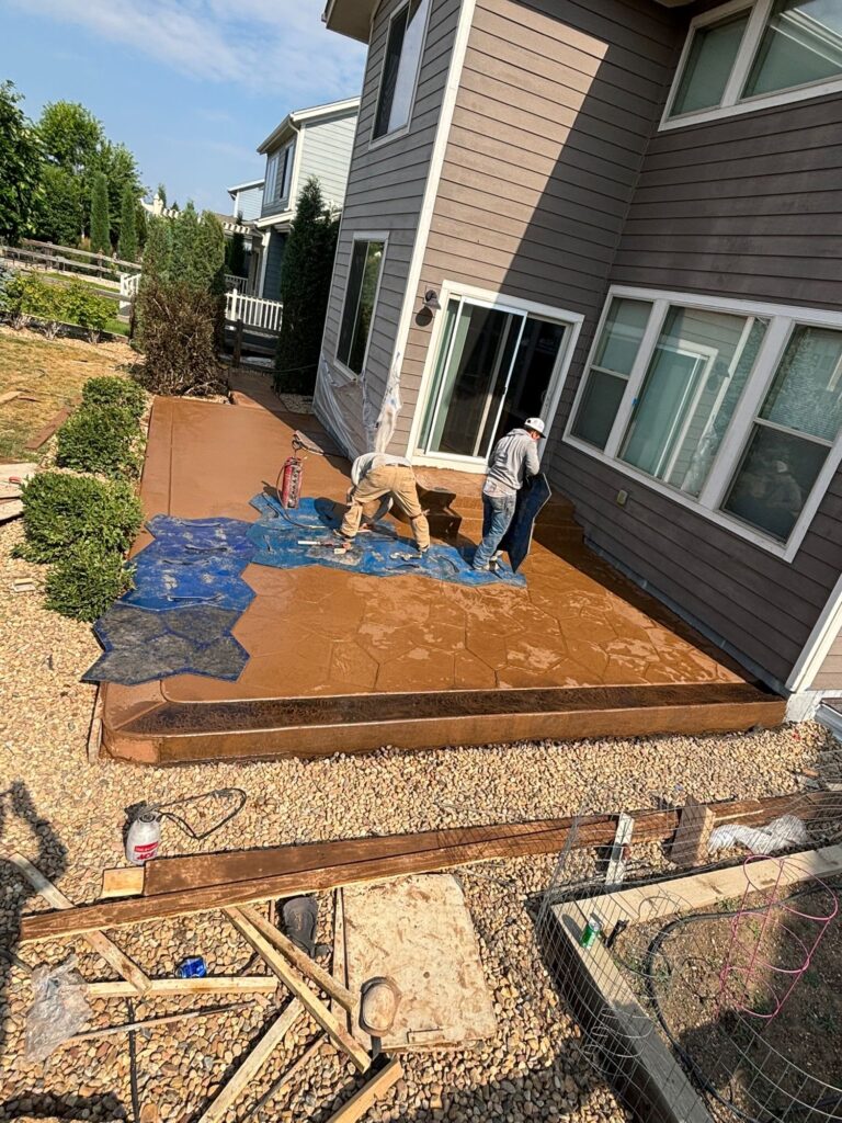 Homeowners working on a cheap DIY concrete patio project using stamped concrete design ideas for a backyard patio in Northern Colorado.