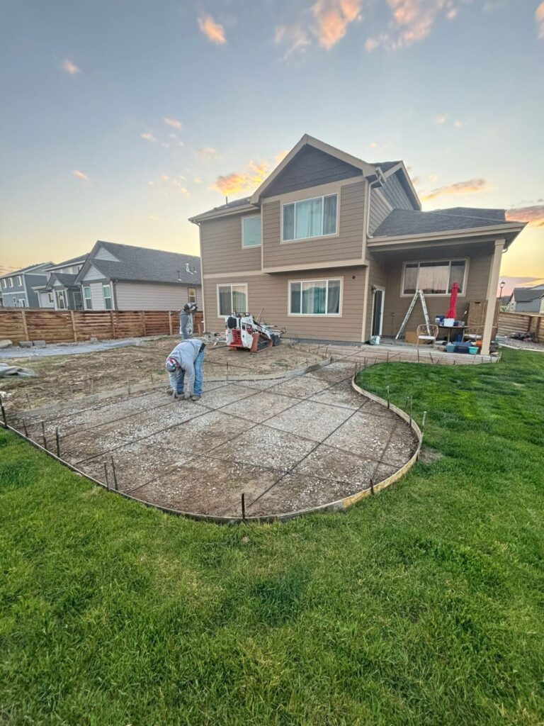 Compacted ground with rebar being installed before concrete walkway and patio pour in Greeley, CO